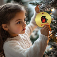 Gold round hanging ornament with red-and-black horned female face and holly