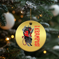 Gold round Krampus holiday ornament hanging on a tree branch with red lettering
