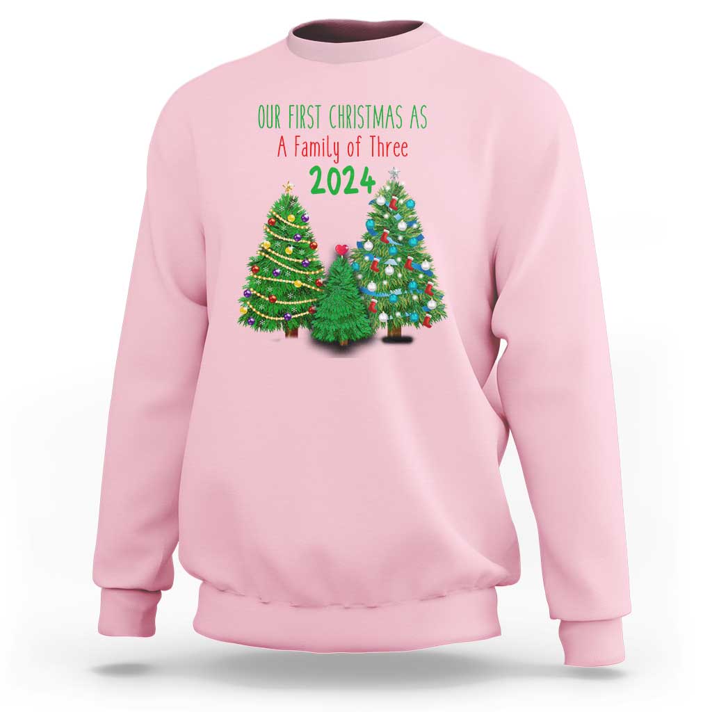 Light pink Christmas sweatshirt with “Our First Christmas As A Family of Three 2024” graphic