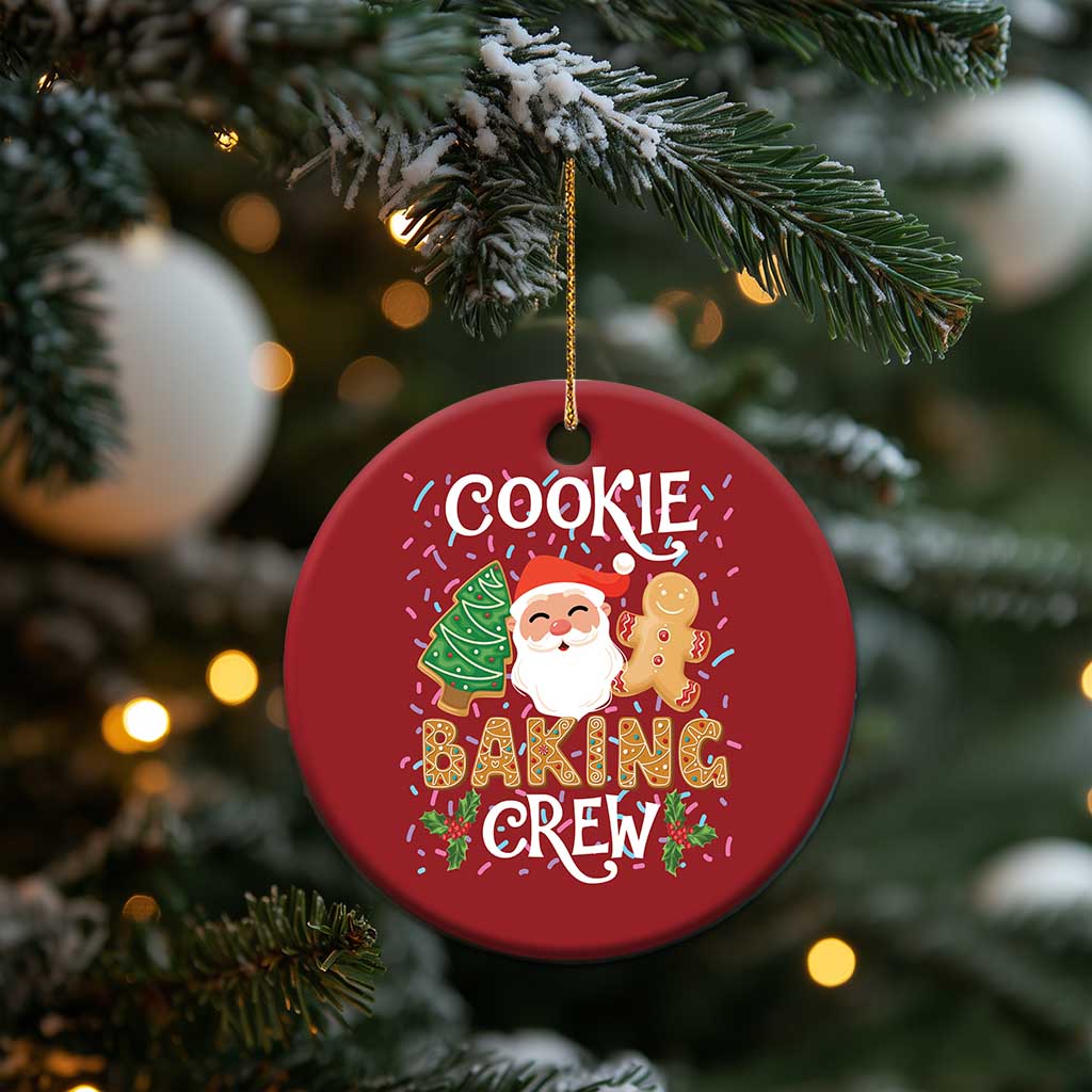 Red round cookie baking crew ornament hanging on a Christmas tree with Santa and gingerbread.