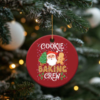 Red round cookie baking crew ornament hanging on a Christmas tree with Santa and gingerbread.