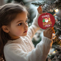 Red round cookie baking crew ornament held near a child’s hand; Santa and gingerbread design.