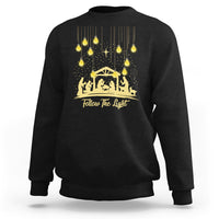 Black Christmas light graphic sweatshirt with gold nativity scene and “Follow The light” text