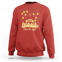 Red Christmas light graphic sweatshirt with gold nativity scene and “Follow The light” text