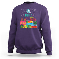 Purple crewneck sweatshirt with “Hello” graphic and multicolor globe print on front.