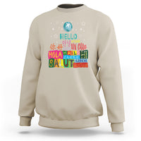 Sand beige crewneck sweatshirt with “Hello” graphic and multicolor globe print on front.