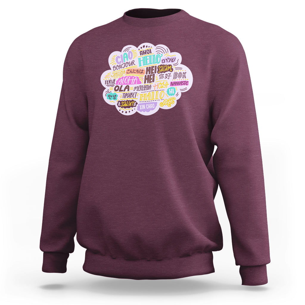 Maroon sweatshirt with multicolor circular “hello” greetings graphic on the chest