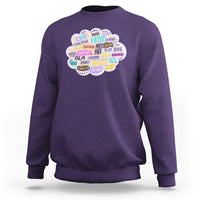 Purple sweatshirt with multicolor circular “hello” greetings graphic on the chest