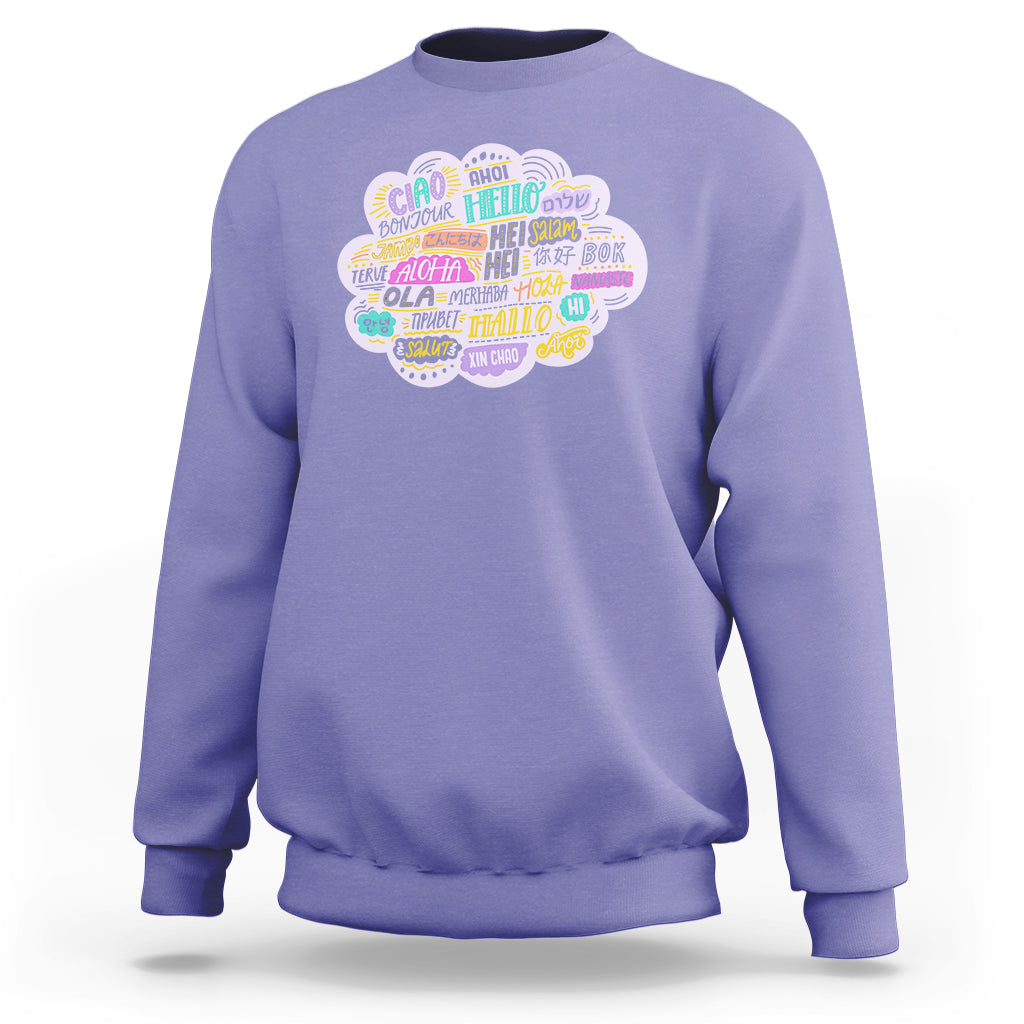Light purple sweatshirt with multicolor circular “hello” greetings graphic on the chest