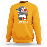Gold crewneck sweatshirt with US EH graphic and Canada–US flag hair illustration
