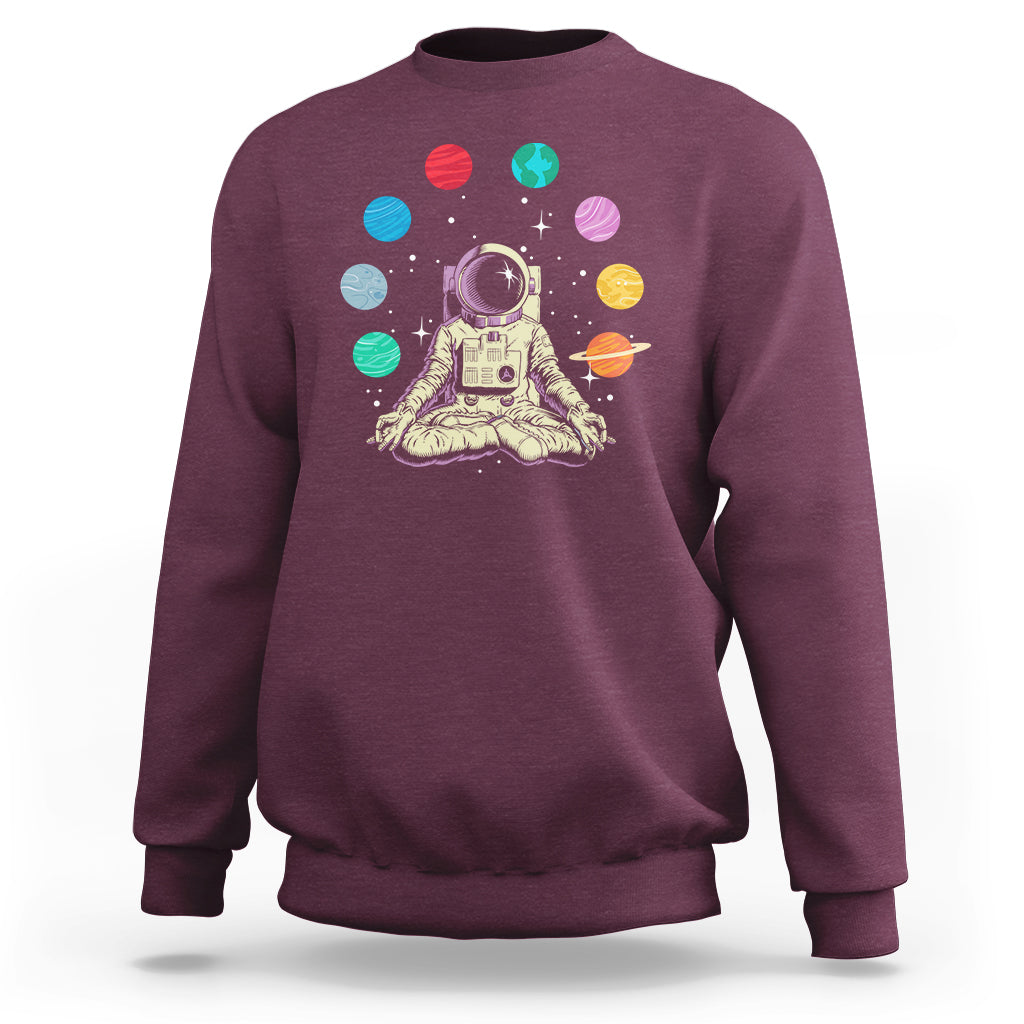 Maroon sweatshirt with astronaut meditating graphic and colorful solar system planets print
