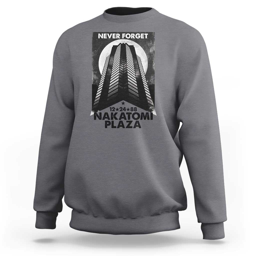 Charcoal crewneck sweatshirt with front graphic print reading “NEVER FORGET” and “NAKATOMI PLAZA”