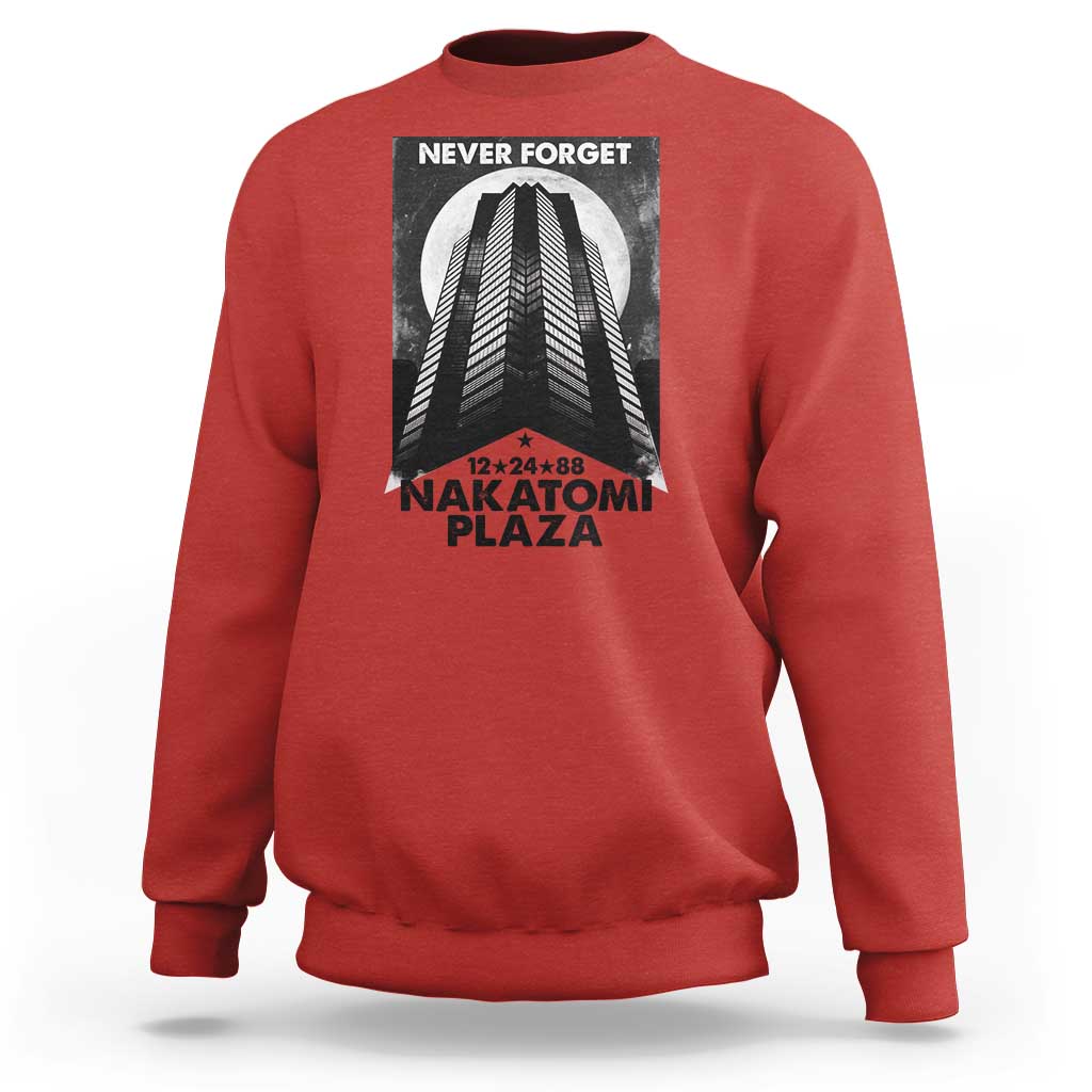 Red crewneck sweatshirt with front graphic print reading “NEVER FORGET” and “NAKATOMI PLAZA”