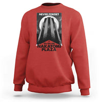 Red crewneck sweatshirt with front graphic print reading “NEVER FORGET” and “NAKATOMI PLAZA”
