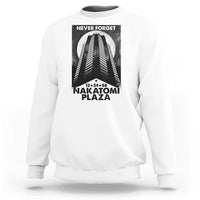 White crewneck sweatshirt with front graphic print reading “NEVER FORGET” and “NAKATOMI PLAZA”