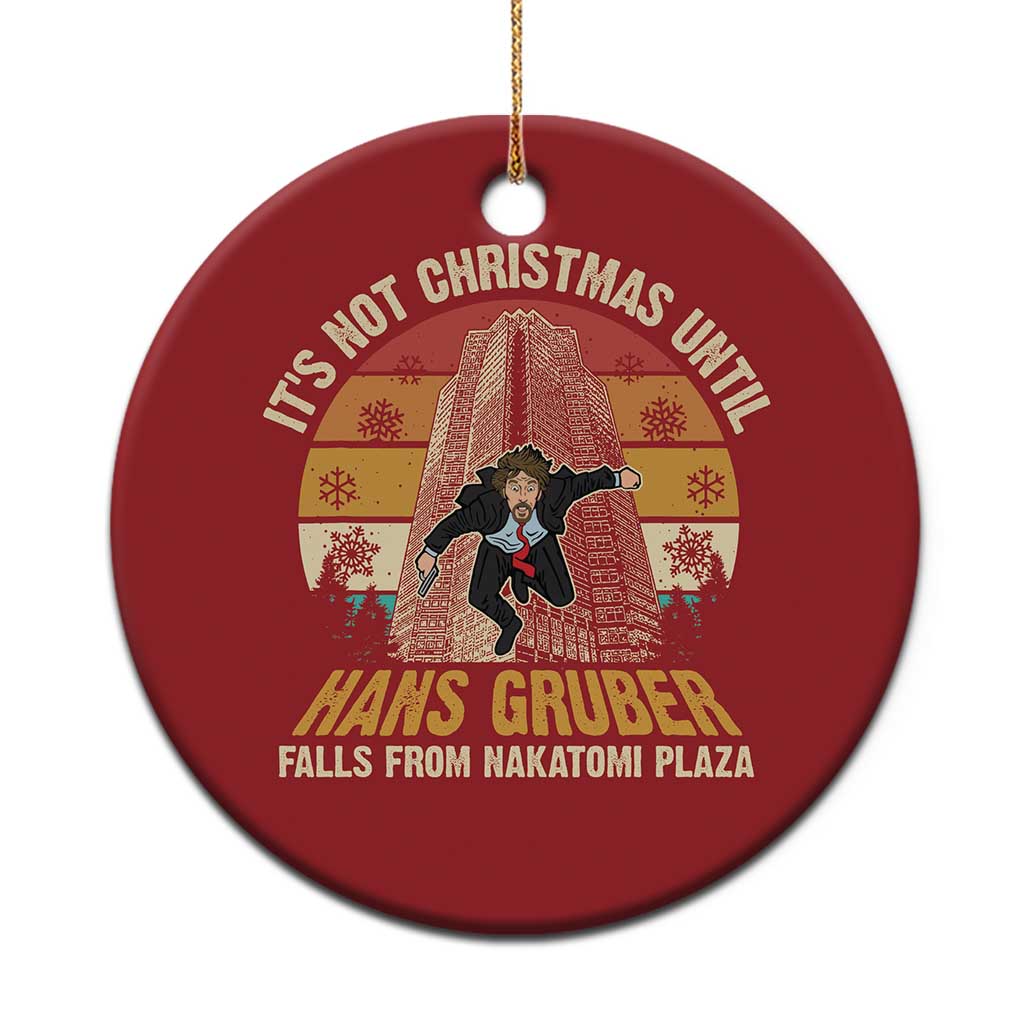 Red circular Christmas ornament with text and graphic design, hanging from a gold string