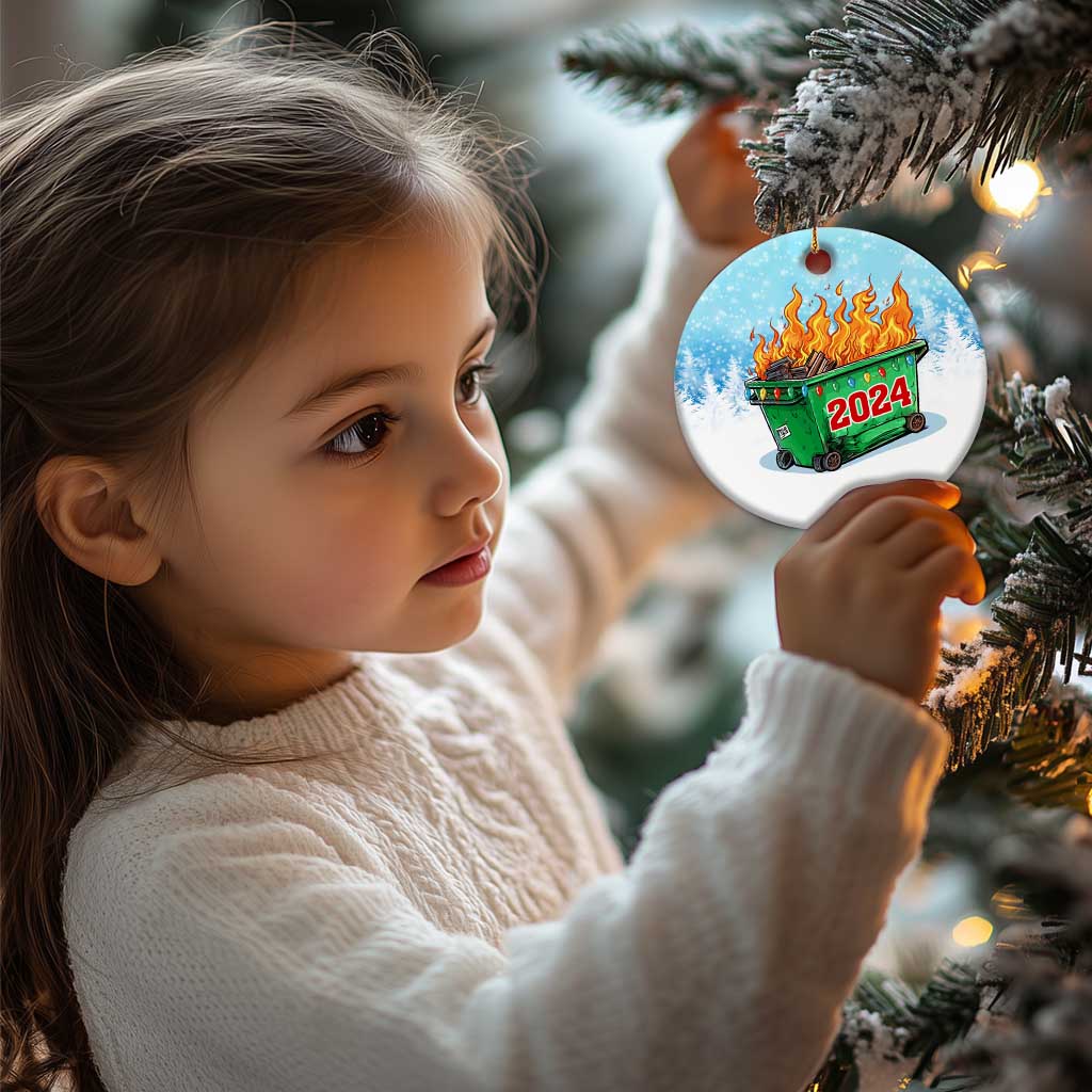 Small round blue Christmas ornament on gold string, green dumpster fire with red 2024.