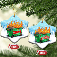 Pair of heart-shaped blue ornaments with green dumpster fire and red 2024 on snowy background.