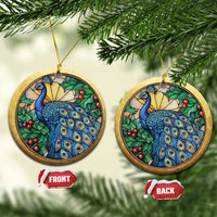Two gold round peacock bird ornaments with blue feathers, green leaves, and red berries