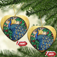 Two gold heart-shaped peacock bird ornaments with blue feathers and red berries