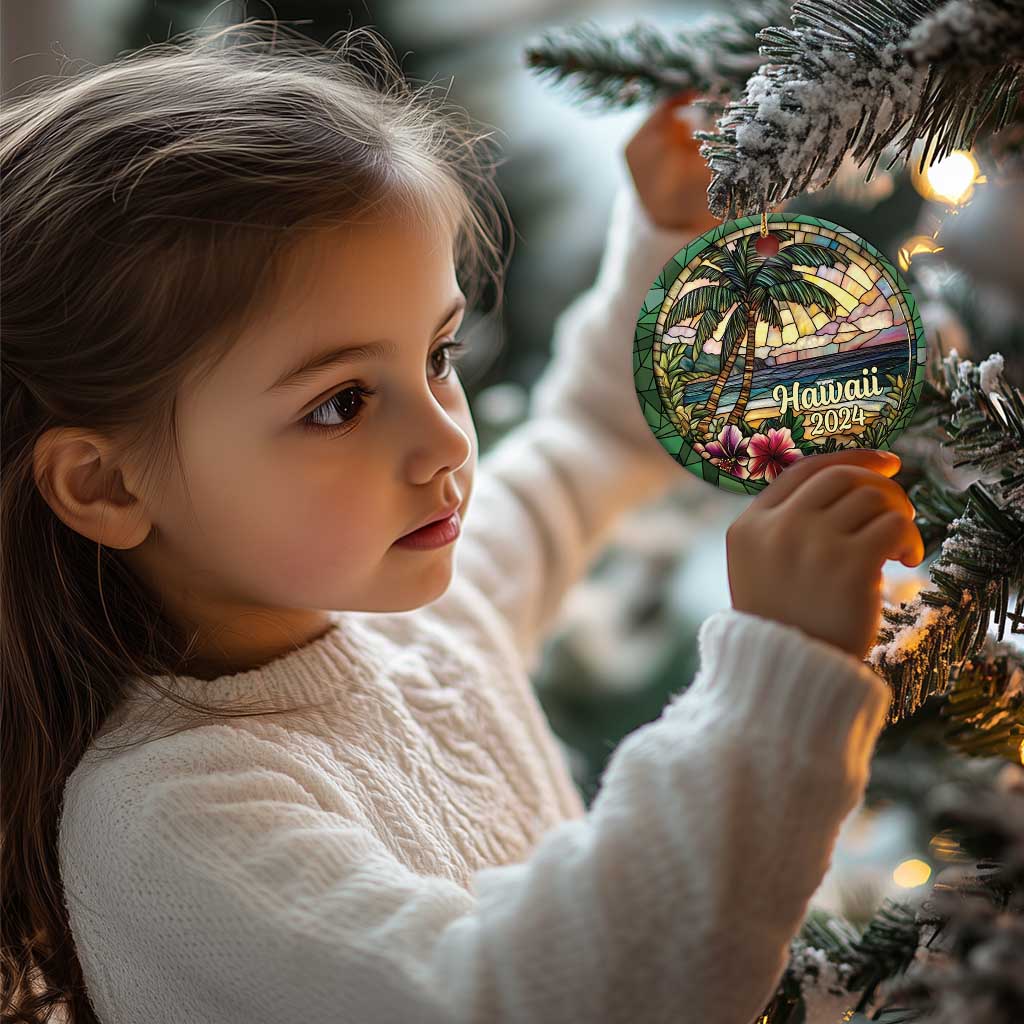 Hawaii 2024 circle ornament on a gold cord, held near holiday pine branches