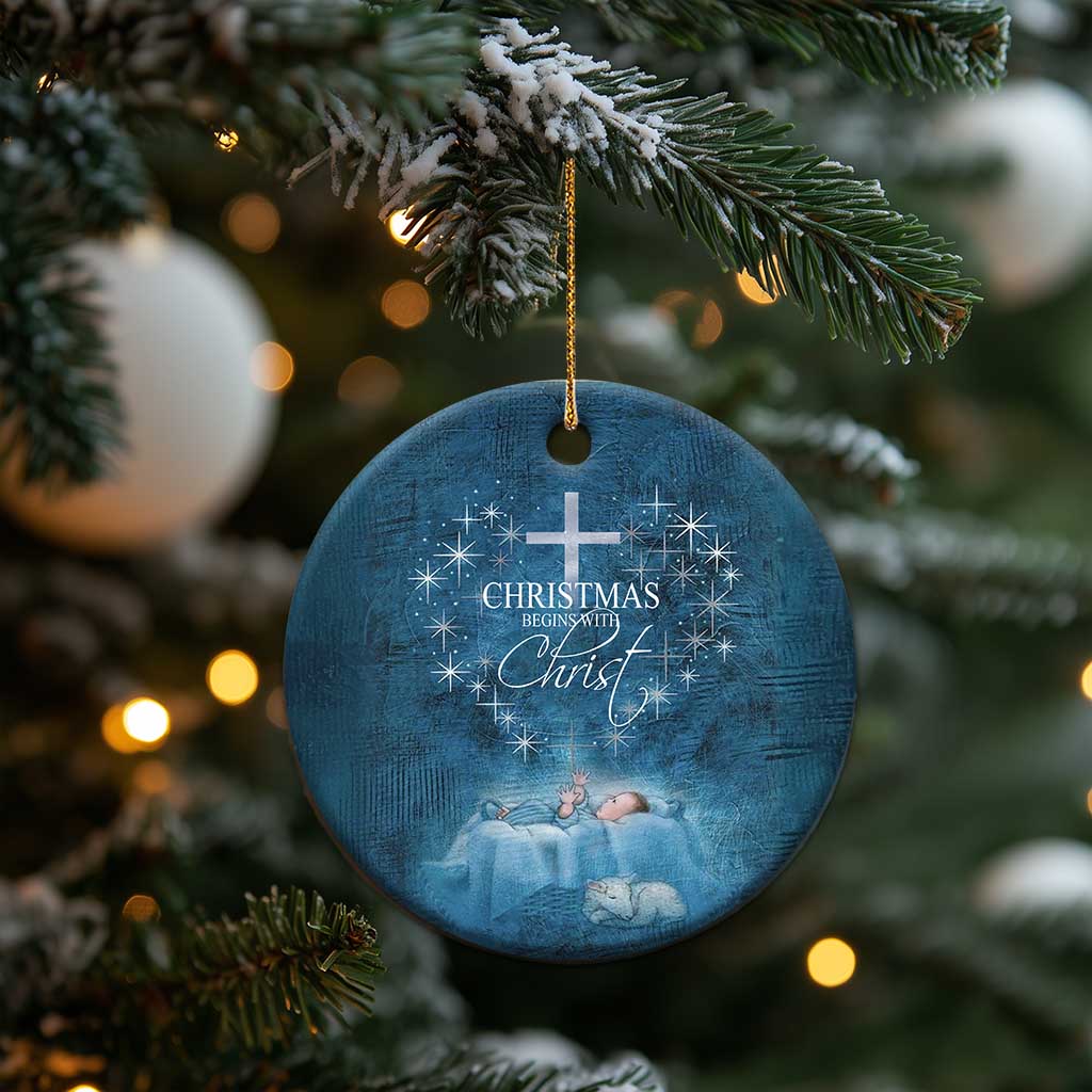 Blue round ornament hanging on a Christmas tree with cross and 'Christmas begins with Christ'