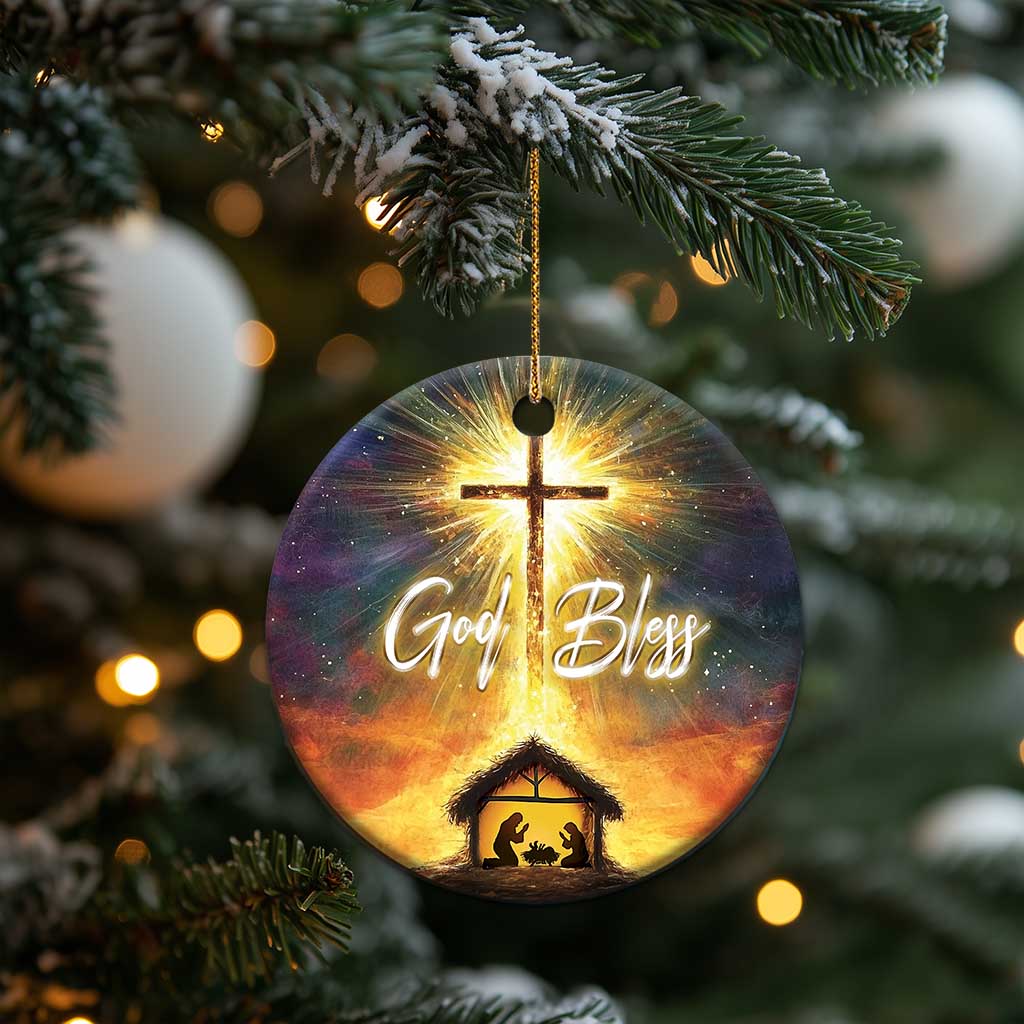 Round nativity Christmas ornament with glowing cross and “God Bless” hanging from gold string