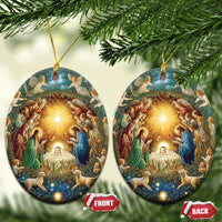 Pair of oval nativity ornaments with gold hanging cords and illuminated manger scene