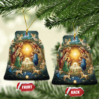 Pair of bell-shaped nativity ornaments with gold hanging cords and glowing manger art