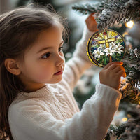 Round stained-glass style cross ornament with white flowers held near a tree