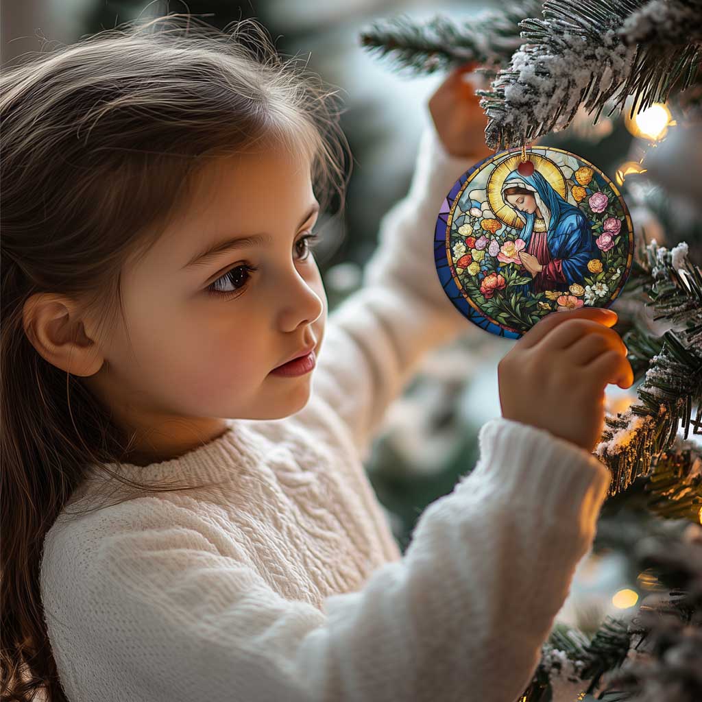 Circular Christian Christmas ornament with Mary in blue robe and colorful flowers, hanging from tree branch