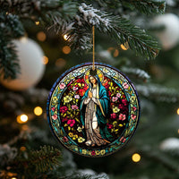 Round Mary stained-glass ornament hanging from a pine tree branch with gold cord