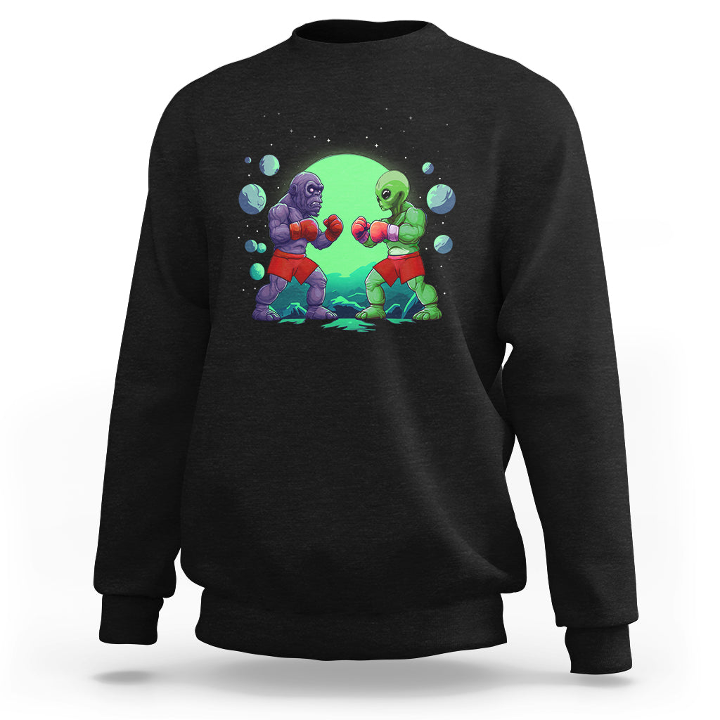 Black crewneck sweatshirt with boxing Bigfoot vs alien graphic on the front.