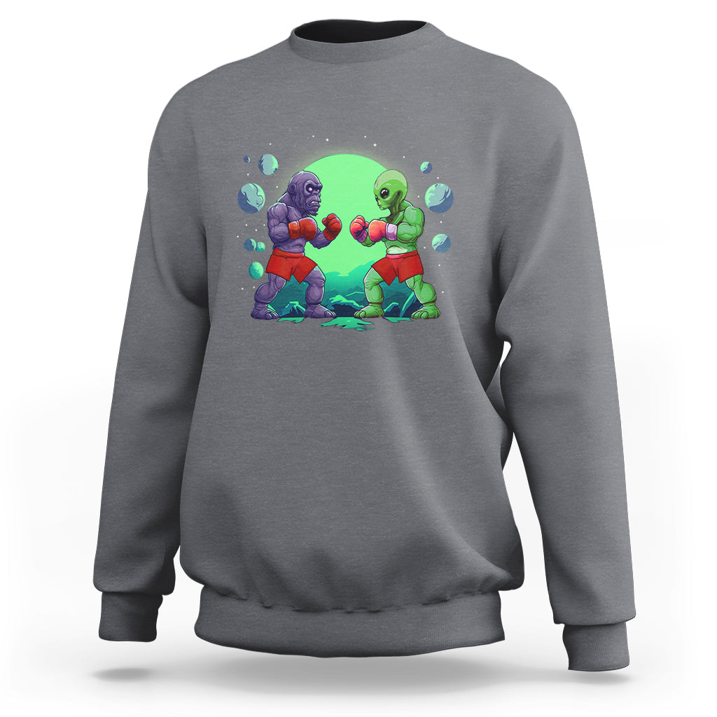 Charcoal gray crewneck sweatshirt with boxing Bigfoot vs alien graphic on the front.