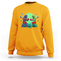 Gold crewneck sweatshirt with boxing Bigfoot vs alien graphic on the front.
