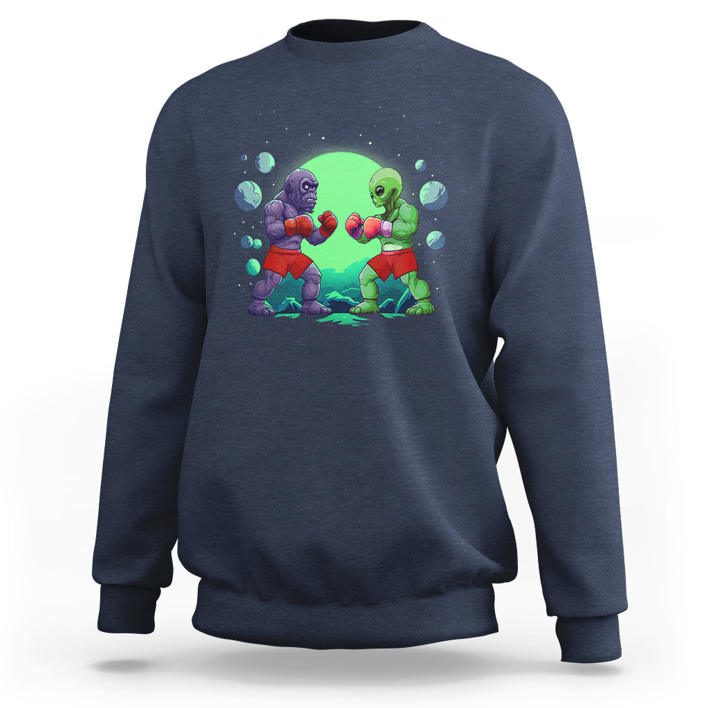 Navy crewneck sweatshirt with boxing Bigfoot vs alien graphic on the front.