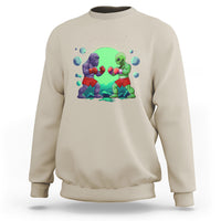 Sand color crewneck sweatshirt with boxing Bigfoot vs alien graphic on the front.