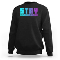 Black crewneck sweatshirt with large colorful “your story isn’t over” graphic on chest