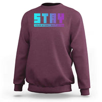 Maroon crewneck sweatshirt with colorful “your story isn’t over” graphic on chest