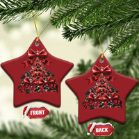 Two red star-shaped Christmas tree ornaments on gold strings among evergreen branches