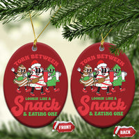 Two red round Christmas ornaments with cartoon “Torn Between” snack text and gold hanging loops