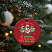 Red round Christmas ornament on tree branch with cartoon “Torn Between” snack text