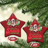 Two red star-shaped Christmas ornaments with cartoon “Torn Between” snack design and gold loops