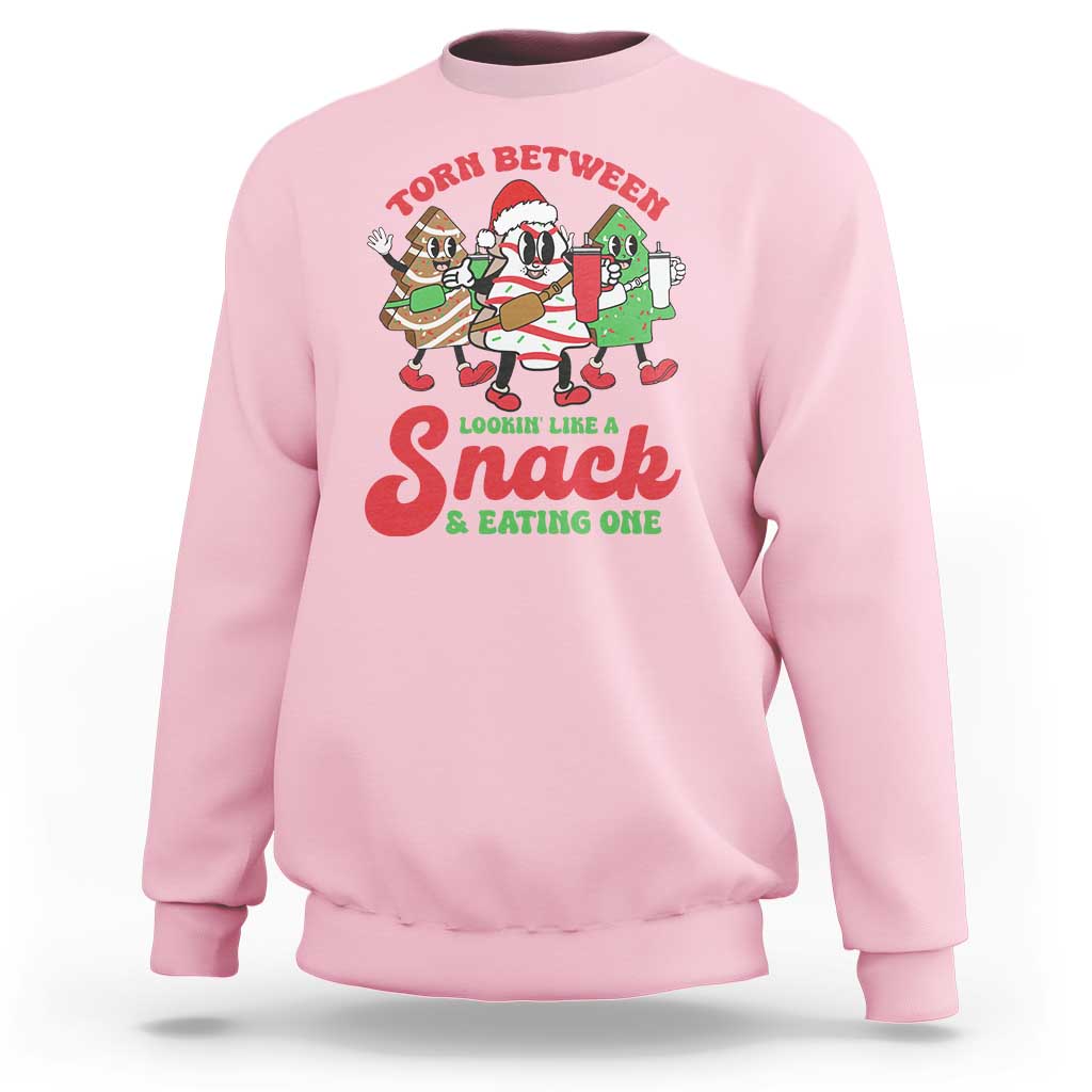 Light pink Christmas cake sweatshirt with large chest graphic reading “Lookin like Snack & eating one”.