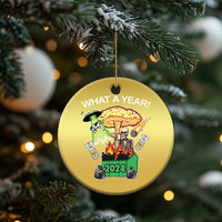 Gold round Christmas ornament hanging from pine branches, “WHAT A YEAR!” skeleton 2024