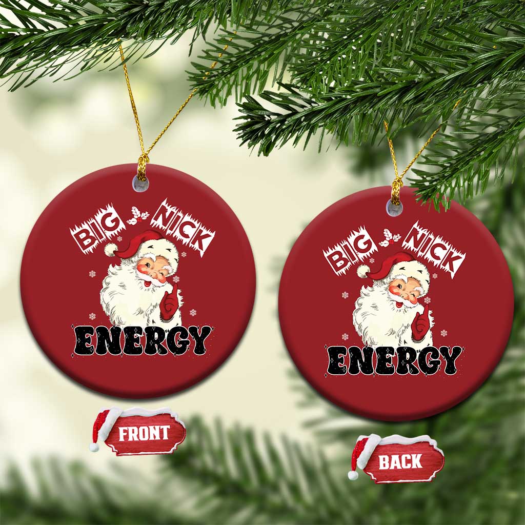 Two red round Santa “Big Nick Energy” ornaments hanging from tree branches