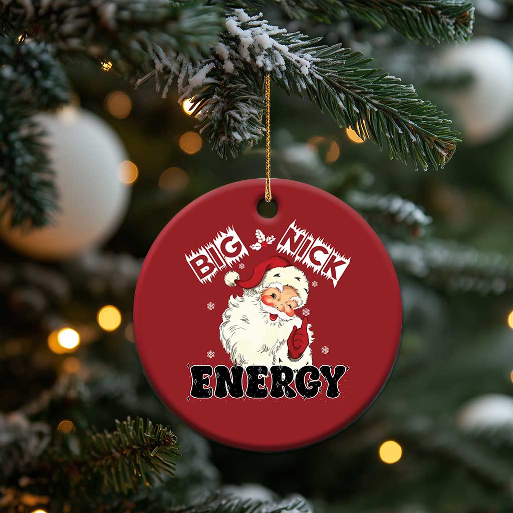 Red round Santa “Big Nick Energy” ornament hanging on evergreen branch