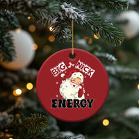 Red round Santa “Big Nick Energy” ornament hanging on evergreen branch