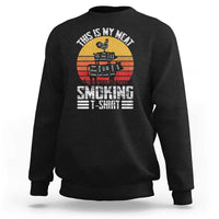 Black crewneck sweatshirt with BBQ smoker graphic and “Smoking” text on front