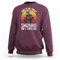 Maroon crewneck sweatshirt with BBQ smoker graphic and “Smoking” text on front
